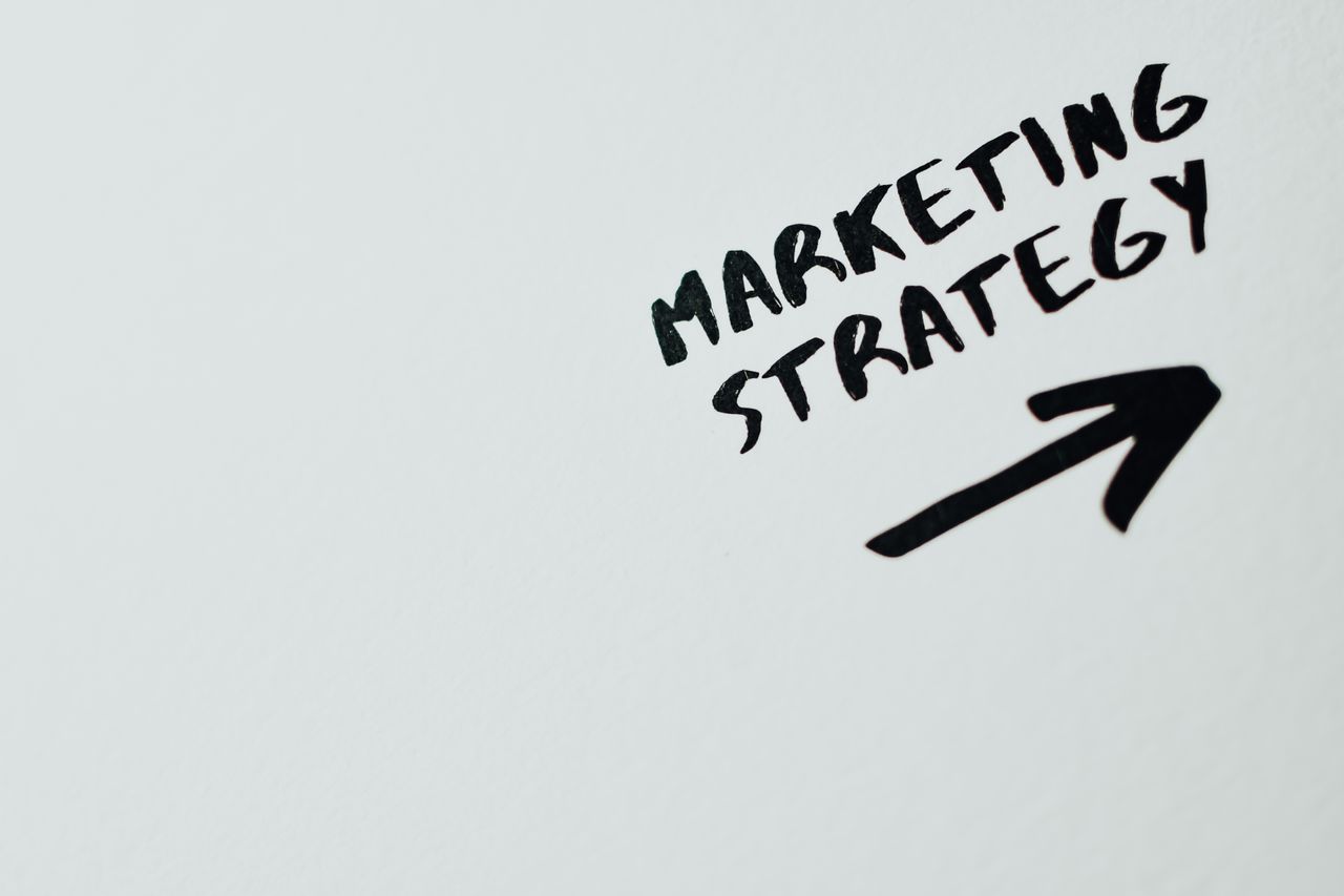 services-02 Close-up of handwritten Marketing Strategy text with an arrow on white background.